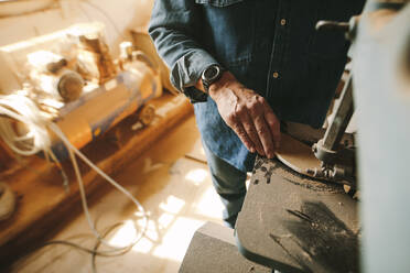 Arbeiter in der Tischlerei schneidet und formt das Holz mit der Bandsäge. Schwerpunkt auf der Handarbeit in der Tischlerei. - JLPSF24668