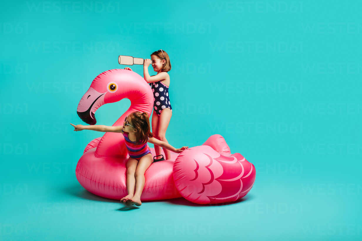 Free Photo  Slim amazing girl in vintage bodysuit kissing big toy bird,  standing in front of pink wall. portrait of cute shapely young woman  holding inflatable flamingo, posing with plants on