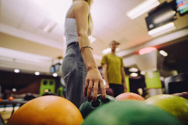 Frau wählt eine Bowlingkugel aus, Nahaufnahme einer weiblichen Hand, die eine Kugel im Bowlingclub aufnimmt. - JLPSF24752