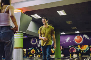 Gutaussehende junge Männer nach dem Werfen einer Bowlingkugel im Club. Paar spielt im Bowlingclub. - JLPSF24755