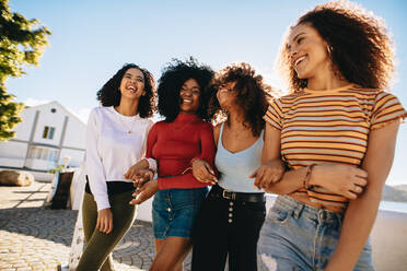 Gemischte Gruppe von Freundinnen, die gemeinsam im Freien spazieren gehen. Junge Frauen, die sich am Strand amüsieren. - JLPSF24757