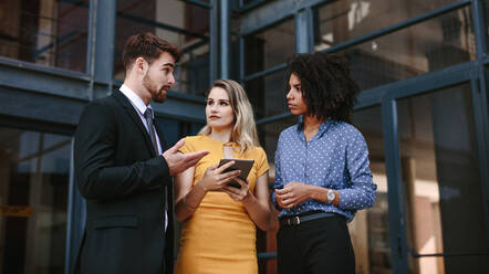 Small group of business people discussing work. Three business professionals talking over new business plan. - JLPSF24827