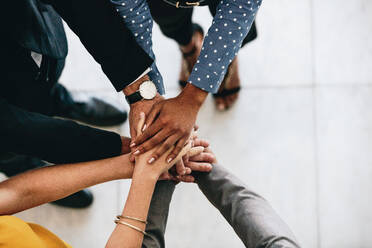 Close up of business team hands stacked together. Business colleagues showing unity. - JLPSF24857