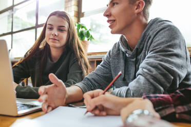 College-Studenten arbeiten an einem Schulprojekt in der Bibliothek, sitzen am Tisch mit Laptop und Büchern. Junge Universitätsstudenten studieren in der Bibliothek. - JLPSF24893