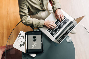 High angle view of a senior graphic designer typing on a laptop while sitting at her desk. Top view of a creative businesswoman working from home. - JLPSF25291