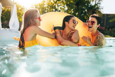 Mädchen genießen einen Tag im Schwimmbad mit aufblasbarem Ring. Lächelnde Freundinnen haben Spaß im Schwimmbad. - JLPSF25306