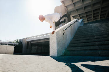 Junger Sportler, der Parkour und freies Laufen im Freien übt, indem er eine Wanddrehung macht. - JLPSF25331