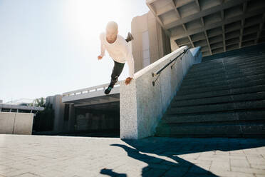 Urbaner Freerunner macht eine Wanddrehung. Junger Sportler übt Parkour und Freerunning im Freien. Parkour in einem urbanen Raum. - JLPSF25332