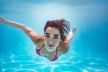 Schöne Frau schwimmt unter Wasser im Pool. Schwimmerin im Bikini am Urlaubsort. - JLPSF25380