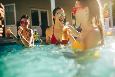 Party im Schwimmbad: Eine Gruppe fröhlicher Frauen trinkt Bier im Schwimmbad. - JLPSF25426