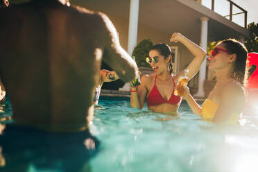 Junge Leute schwimmen und trinken Biere bei einer Poolparty. - JLPSF25427