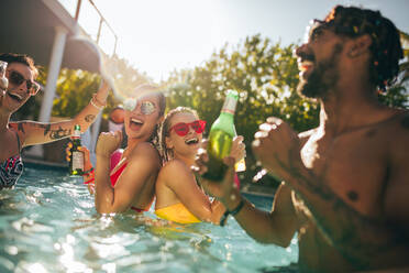 Gruppe von glücklichen Freunden am Pool Party mit Bieren. Männer und Frauen Menschen lachen und haben Spaß im Schwimmbad. - JLPSF25434