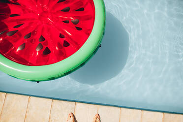 Draufsicht auf eine bunte aufblasbare Wassermelone, die an einem Sommertag in einem Schwimmbad schwimmt. - JLPSF25474