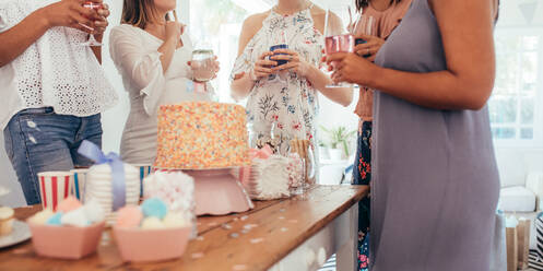 Cropped Schuss von Kuchen und süßen Speisen auf dem Tisch mit Frauen stehen um Getränke auf Baby-Dusche-Party. weibliche Freunde genießen Baby-Dusche-Party. - JLPSF25493