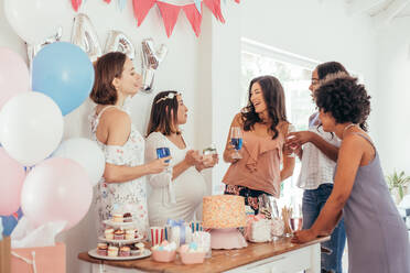 Schwangere Frau feiert Babyparty mit Freundinnen zu Hause. Gruppe von multiethnischen Frauen bei einer Babyparty. - JLPSF25494