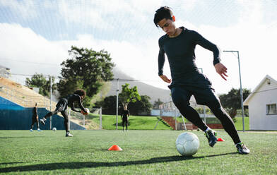 Fußballspieler beim Training auf dem Fußballplatz. Junger Fußballspieler übt Ballkontrolle beim Training. - JLPSF25500