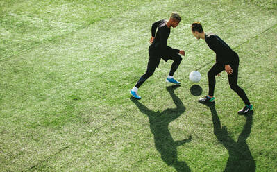 Draufsicht auf zwei Jugendliche beim Fußballspielen während des Mannschaftstrainings auf einem Feld. Junge Fußballspieler spielen auf einem Sportrasenplatz. - JLPSF25510