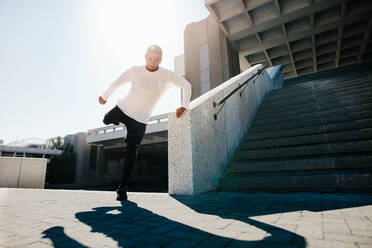 Fit urban guy Durchführung einer Wand Spin im Freien in der Stadt. Junge Sportler üben Parkour und frei laufen. - JLPSF25538