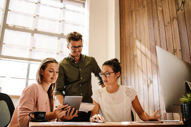 Schuss von Business-Team arbeiten zusammen und Blick auf digitale Tablet. Geschäftsmann und Geschäftsfrau am Schreibtisch im modernen Büro. - JLPSF25565