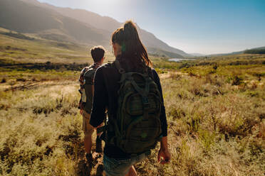 Rückansicht eines jungen Mannes und einer Frau, die auf einem Wanderweg wandern. Junges Paar mit Rucksack beim Wandern in extremem Gelände. - JLPSF25581