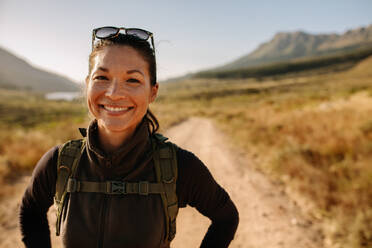 Close up Porträt der lächelnden jungen asiatischen Frau mit Rucksack auf dem Land wandern. Glückliche Frau auf einer Wanderung in der Natur. - JLPSF25642