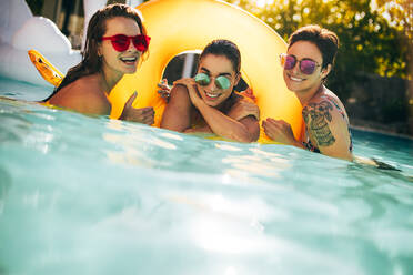 Porträt von schönen Frauen zusammen im Pool mit einem schwimmenden Ring. Weibliche Freunde haben Spaß in einem Schwimmbad. - JLPSF25656