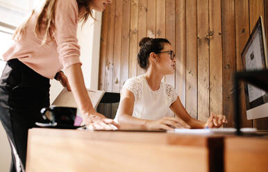 Zwei Geschäftsfrauen arbeiten gemeinsam an einem Projekt im Büro. Weibliche Kollegen am Schreibtisch, die auf den Computerbildschirm schauen. - JLPSF25670