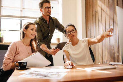 Kollegen, die auf einen Computer schauen und eine neue Geschäftsidee diskutieren. Kreatives Business-Team, das im Büro gemeinsam am Computer arbeitet. - JLPSF25674