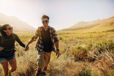 Glücklicher junger Mann und Frau wandern an einem sonnigen Tag. Schönes Paar auf Wanderweg im Naturschutzgebiet. - JLPSF25697