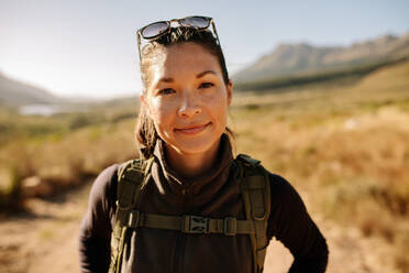 Close up Porträt der jungen asiatischen Frau mit Rucksack auf dem Land wandern. Weiblich auf einer Wanderung in der Natur. - JLPSF25699