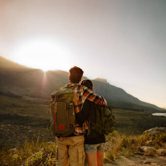 Rückansicht eines jungen Mannes und einer Frau, die an einem sonnigen Tag wandern. Verliebtes Paar auf einem Wanderweg in einem Naturschutzgebiet mit Blick auf eine schöne Aussicht. - JLPSF25707