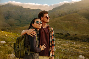 Aufnahme eines jungen Mannes und einer Frau auf einem Wanderausflug, die zusammen stehen und die Aussicht bewundern. Liebendes junges Paar auf Wanderausflug in der Natur. - JLPSF25709