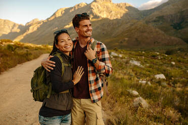 Shot of happy young couple on country walk, standing together and looking at landscape. Young man and woman on hiking trip. - JLPSF25712