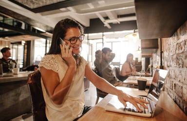 Glückliche Geschäftsfrau im Büro und im Gespräch auf dem Handy. Lässige Geschäftsfrau arbeitet im Startup-Büro. - JLPSF25803