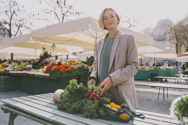 Lächelnde Frau mit Lebensmitteln auf dem Tisch auf dem Markt - NDEF00032