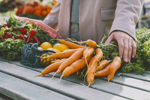 Hands of woman on bunch of carrots at table - NDEF00033