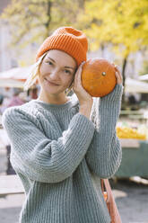 Lächelnde Frau im Pullover mit frischem Kürbis auf dem Markt - NDEF00042