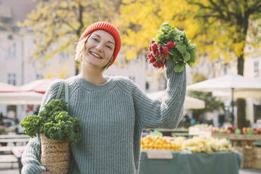 Happy woman holding radish at market - NDEF00046
