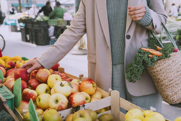 Hand einer Frau, die auf dem Markt frische Äpfel kauft - NDEF00054