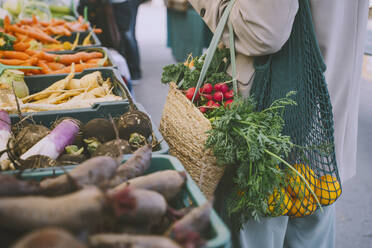 Frau mit Einkaufstüten neben Gemüse in einer Kiste stehend - NDEF00055