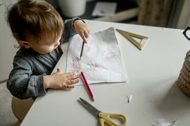 Junge kritzelt mit Bleistift auf Papier zu Hause - ANAF00383