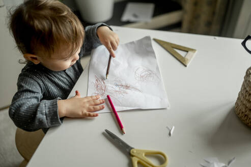 Boy scribbling with pencil on paper at home - ANAF00383