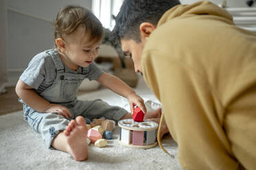 Vater und Sohn spielen zu Hause mit Holzspielzeug - ANAF00407