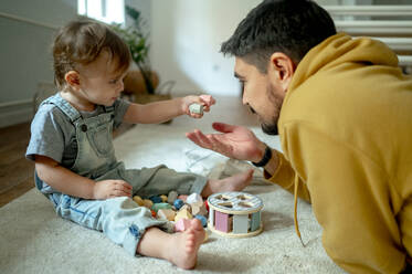 Father and son playing with wooden toys on carpet at home - ANAF00408