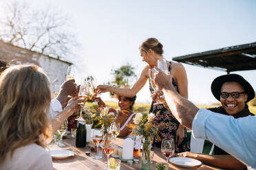 Eine Gruppe von Menschen im Restaurant stößt mit Getränken auf einer Party im Freien an. Junge Freunde auf einer Party genießen Getränke. - JLPSF25815
