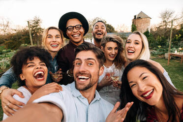 Friends chilling outside taking group selfie and smiling. Laughing young people standing together outdoors and taking selfie. - JLPSF25822