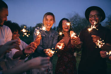 Group of friends enjoying out with sparklers. Young men and women enjoying with fireworks. - JLPSF25825