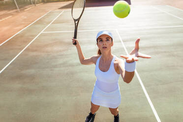 Schöne junge Tennisspielerin, die den Ball aufschlägt. Junge Frau in Sportkleidung beim Tennismatch auf dem Platz. - JLPSF25851