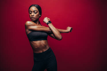 Healthy black woman wearing fitness outfit on red background and