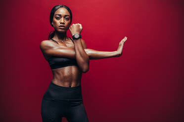 Fit woman doing exercise against red background. African female